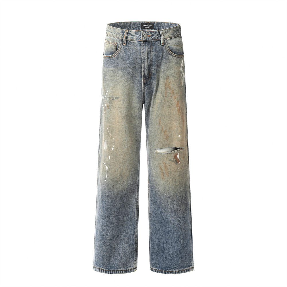 Blue-brown washed jeans with distressed rips and speckled detailing.