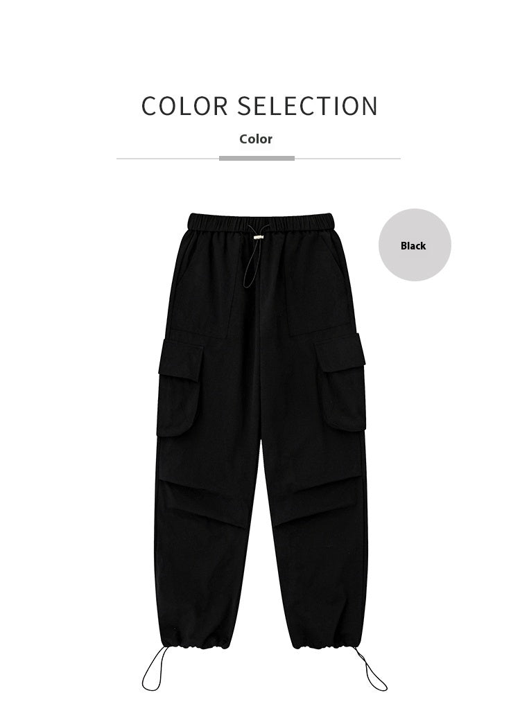Black cargo trousers with elastic drawstring waist, flap thigh pockets and drawcord ankles.